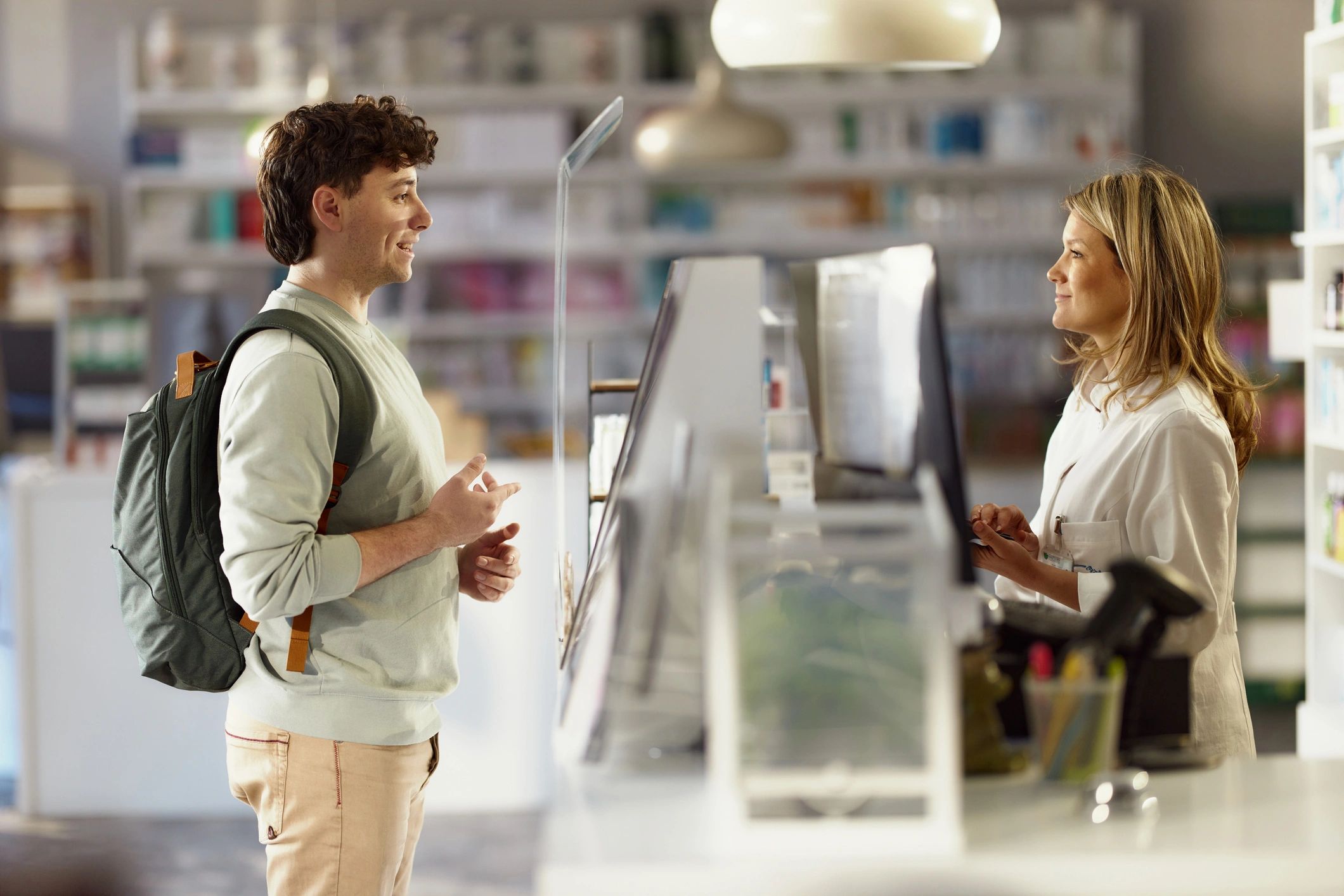 Customer speaking with a pharmacist at a pharmacy counter